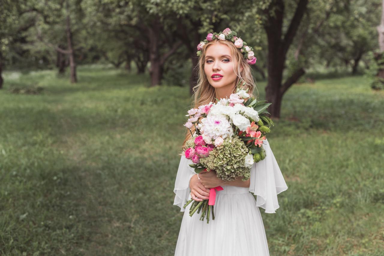 beautiful young Ukrainian blonde woman holding flowers in wedding dress