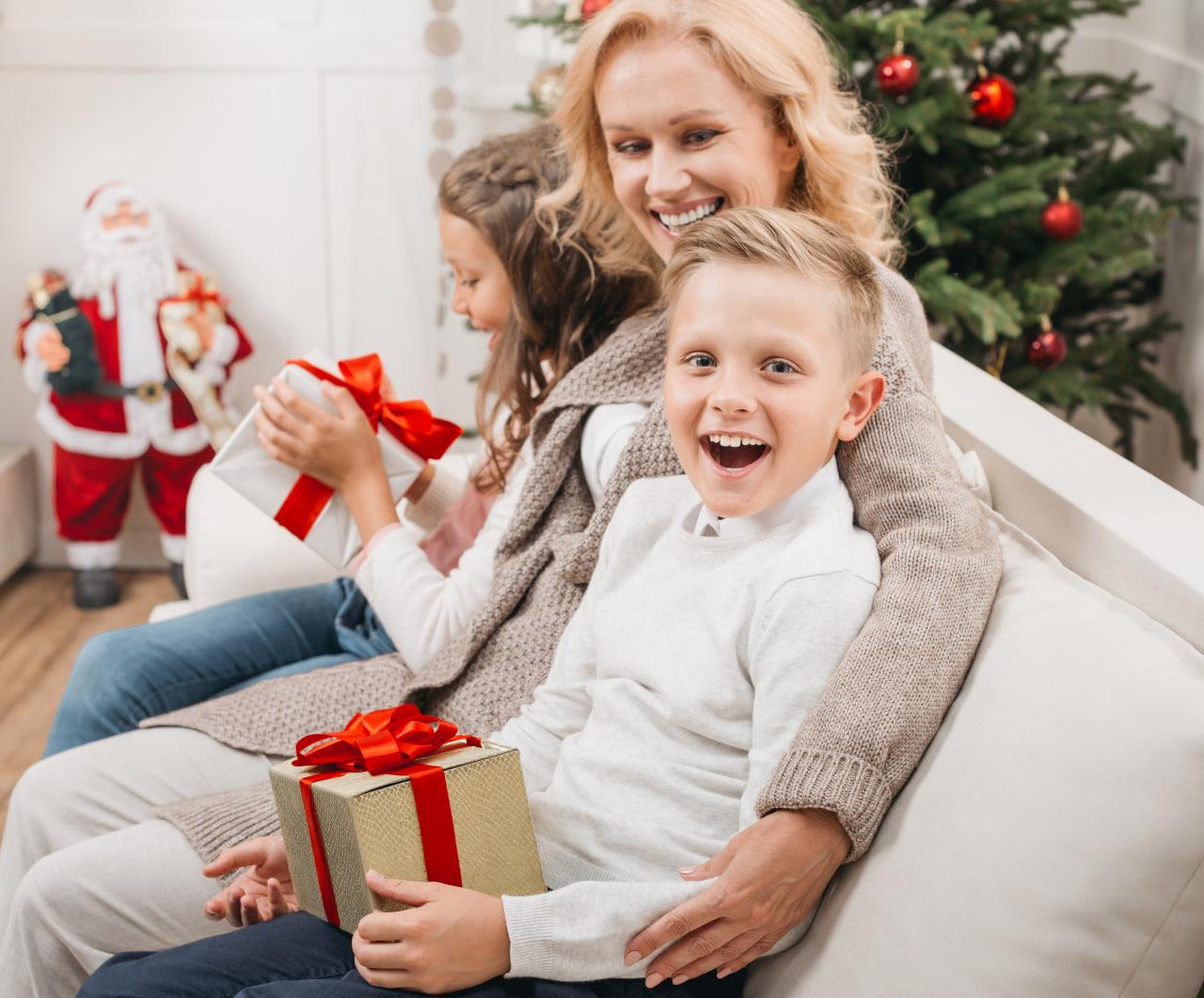 beautiful blonde woman hugging children holding gifts and presents on new year
