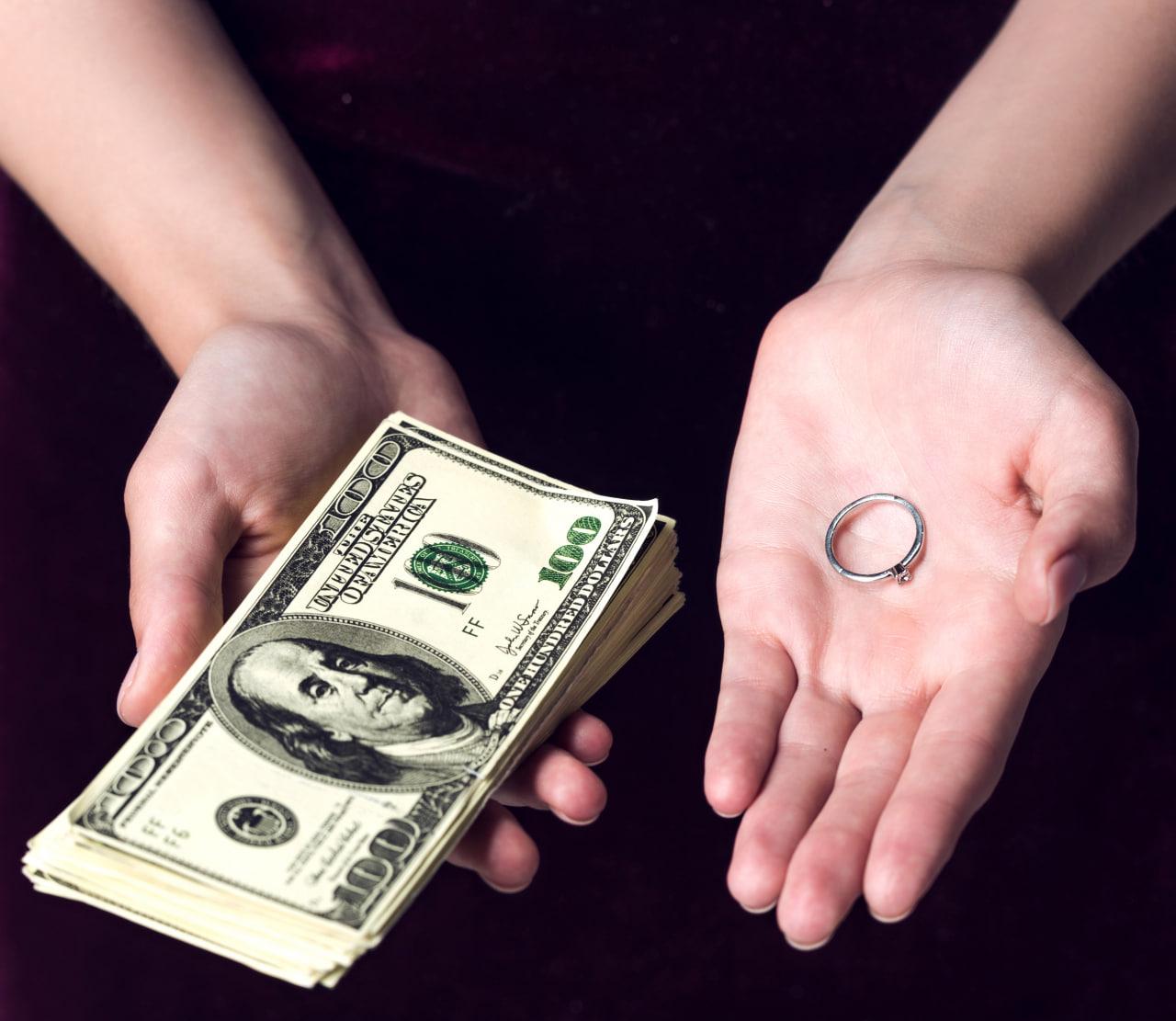 woman holding engagement ring and money